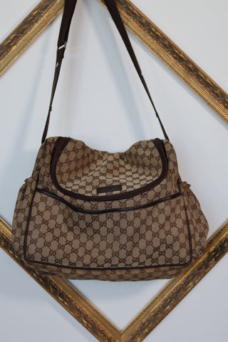 Gucci GG Canvas diaper bag in brown monogram canvas with leather trim and adjustable shoulder strap.