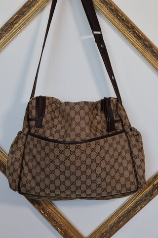 Gucci GG Canvas diaper bag in brown monogram canvas with leather trim and adjustable shoulder strap.