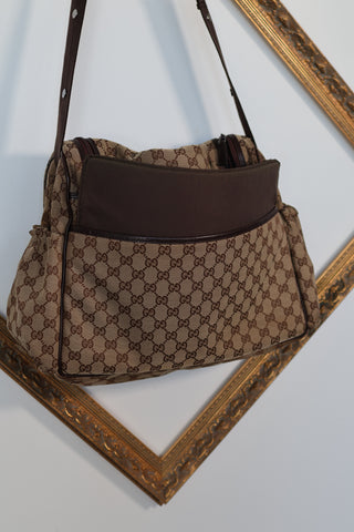 Gucci GG Canvas diaper bag in brown monogram canvas with leather trim and adjustable shoulder strap.
