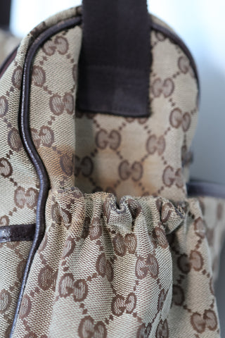 Gucci GG Canvas diaper bag in brown monogram canvas with leather trim and adjustable shoulder strap.