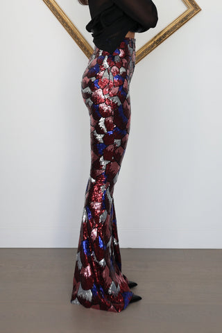 Nadine Merabi geometric sequin flare trousers in burgundy red, blue and silver with a high-waisted fit and statement flared leg silhouette.