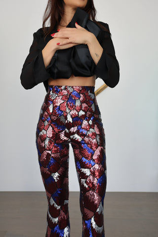 Nadine Merabi geometric sequin flare trousers in burgundy red, blue and silver with a high-waisted fit and statement flared leg silhouette.