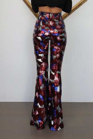 Nadine Merabi geometric sequin flare trousers in burgundy red, blue and silver with a high-waisted fit and statement flared leg silhouette.