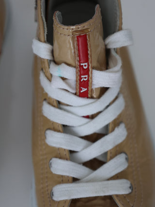 Prada toddler beige patent leather high-top sneakers with lace-up and side zip closure.
