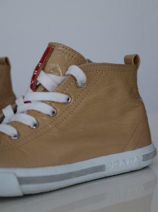 Prada toddler beige patent leather high-top sneakers with lace-up and side zip closure.