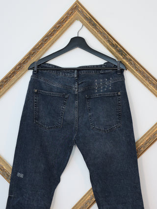 Ksubi navy blue denim jeans with signature back cross embroidery displayed on hanger