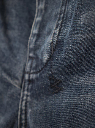 Ksubi navy blue denim jeans with signature back cross embroidery displayed on hanger