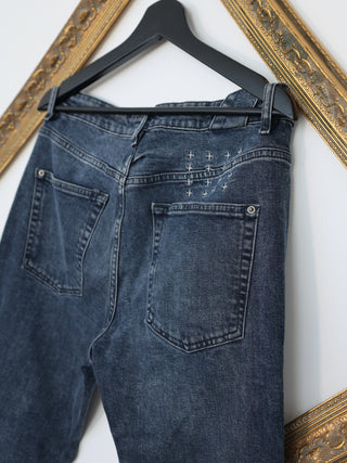 Ksubi navy blue denim jeans with signature back cross embroidery displayed on hanger