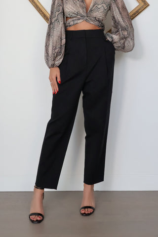 Acne Studios black tailored trousers featuring a mid-rise waist, tapered-leg silhouette, front pleat detailing and minimalist Scandinavian design.