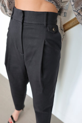 Acne Studios black tailored trousers featuring a mid-rise waist, tapered-leg silhouette, front pleat detailing and minimalist Scandinavian design.