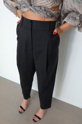 Acne Studios black tailored trousers featuring a mid-rise waist, tapered-leg silhouette, front pleat detailing and minimalist Scandinavian design.