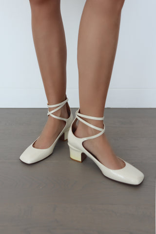 Valentino ivory patent leather ballerina pumps with ankle straps and low block heel, size 40.5, photographed on model.
