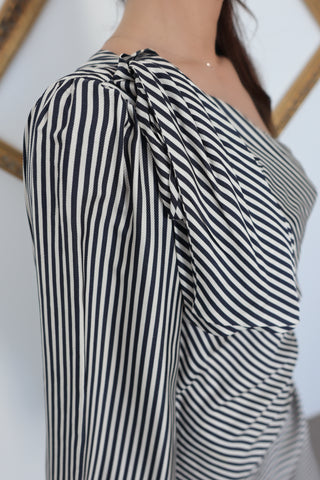 Close-up of the shoulder knot and striped draped sleeve of the Zimmermann one-shoulder mini dress.