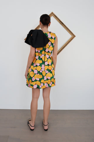 Model wearing Rachel Gilbert embroidered floral knee-length dress with oversized black shoulder bow.