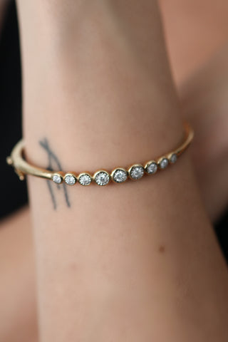 Michael Hill 10K yellow gold diamond bezel-set bangle with round brilliant diamonds.