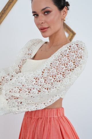 Zimmermann white lace long-sleeve cropped top with structured bodice and voluminous sleeves, worn with coral skirt.