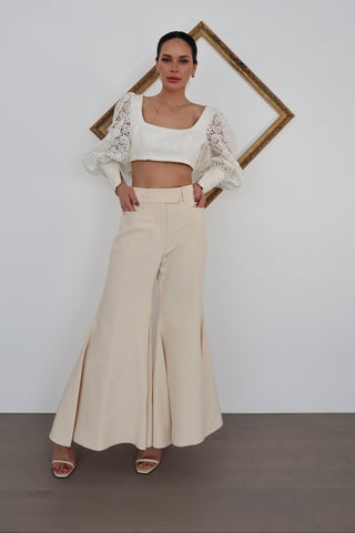 Zimmermann white lace long-sleeve cropped top with structured bodice and voluminous sleeves, worn with coral skirt.