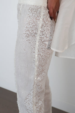 Close-up and full-length photos of Zimmermann transparent white sequin pants worn with white shirt and silver top.