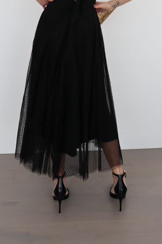 Black Zimmermann polka-dot tulle maxi skirt styled with pointed black heels, showing layered mesh detail.