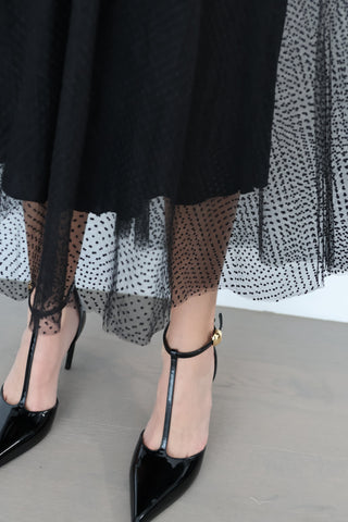 Black Zimmermann polka-dot tulle maxi skirt styled with pointed black heels, showing layered mesh detail.