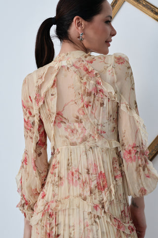 Model wearing Zimmermann floral midi dress in neutral tones with pink flowers, standing against a white background with a tilted gold frame.