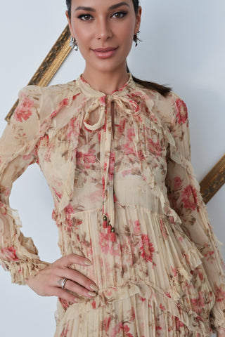 Model wearing Zimmermann floral midi dress in neutral tones with pink flowers, standing against a white background with a tilted gold frame.