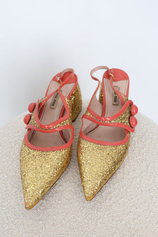 Miu Miu gold glitter pointed-toe pumps in EU Size 40 featuring coral-orange patent leather crossover straps, sculptural button embellishments and glitter-covered low block heels.