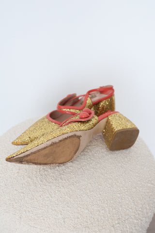 Miu Miu gold glitter pointed-toe pumps in EU Size 40 featuring coral-orange patent leather crossover straps, sculptural button embellishments and glitter-covered low block heels.