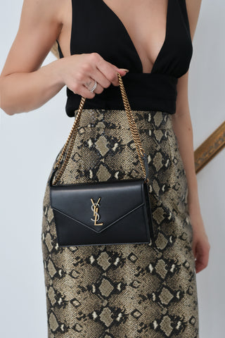 A timeless Saint Laurent classic, the Small Envelope Wallet on Chain is a refined essential crafted from smooth black leather and finished with the iconic gold-toned YSL monogram.